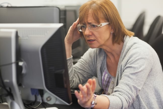 Angry mature student working with computer in computer class